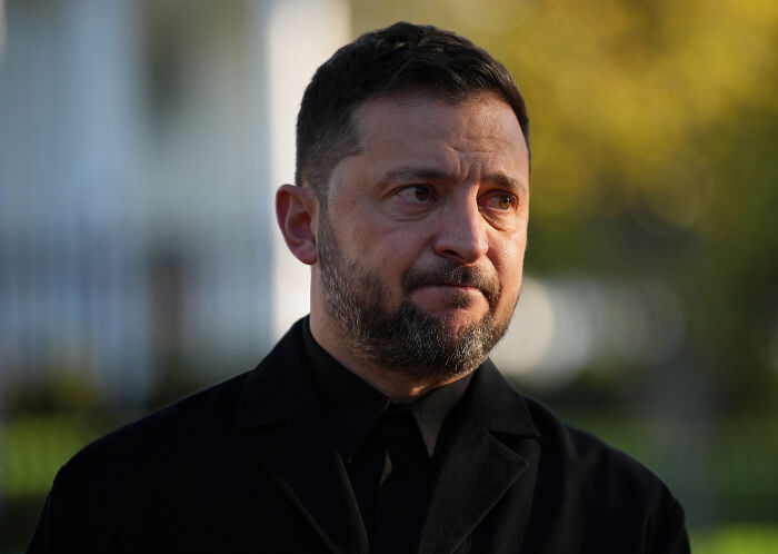 Man in black coat with somber expression outdoors, representing Karoline Leavitt bizarre text clash with journalist.