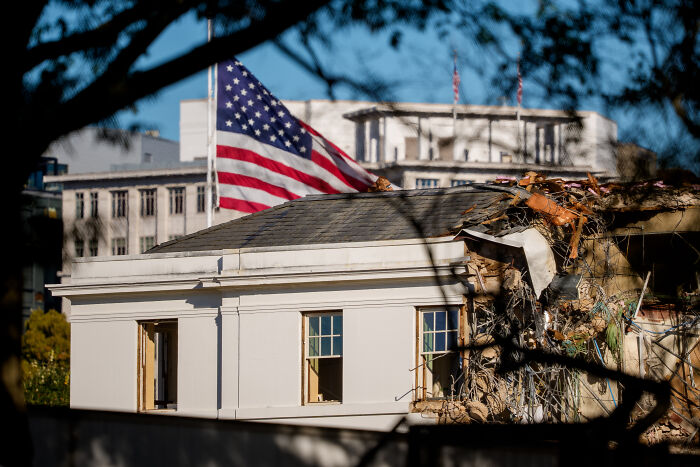 Partial demolition of the historic East Wing building with an American flag in the background during Trump&rsquo;s ballroom project.
