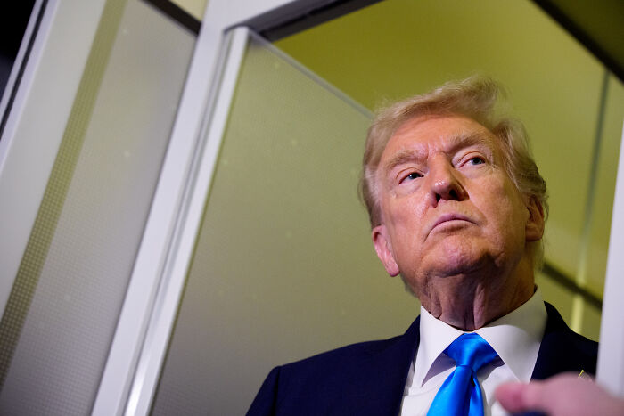 Donald Trump looking upward with serious expression, relating to magnets and steam aboard aircraft carrier discussion.