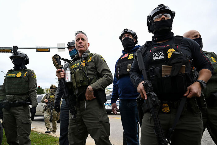 Federal agents in tactical gear armed and standing alert during government shutdown enforcement efforts.