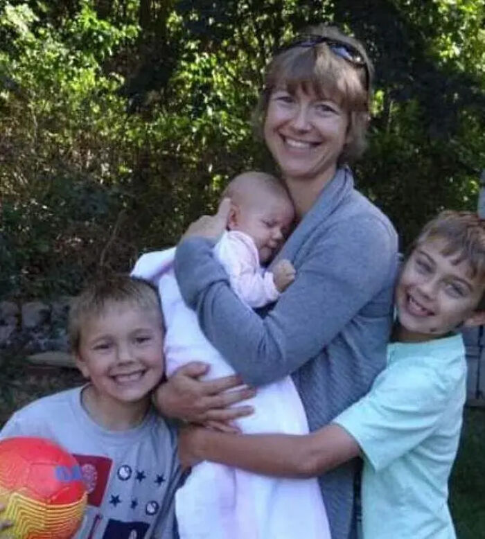 Smiling woman holding baby with two boys hugging her outdoors, related to Florida man unalived wife and children case.