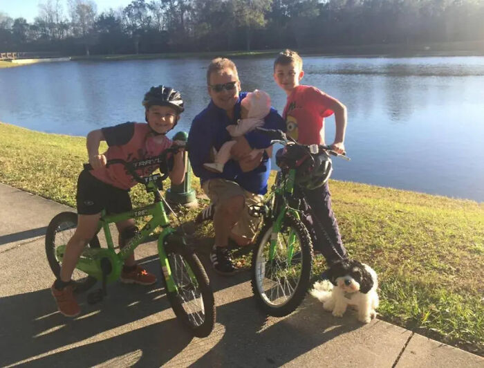 Florida man with wife, three children, and dog by a lake, posing with bicycles and smiling outdoors on a sunny day