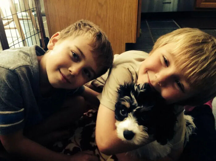 Two young boys smiling and holding a small black and white dog, illustrating Florida man family tragedy keywords.