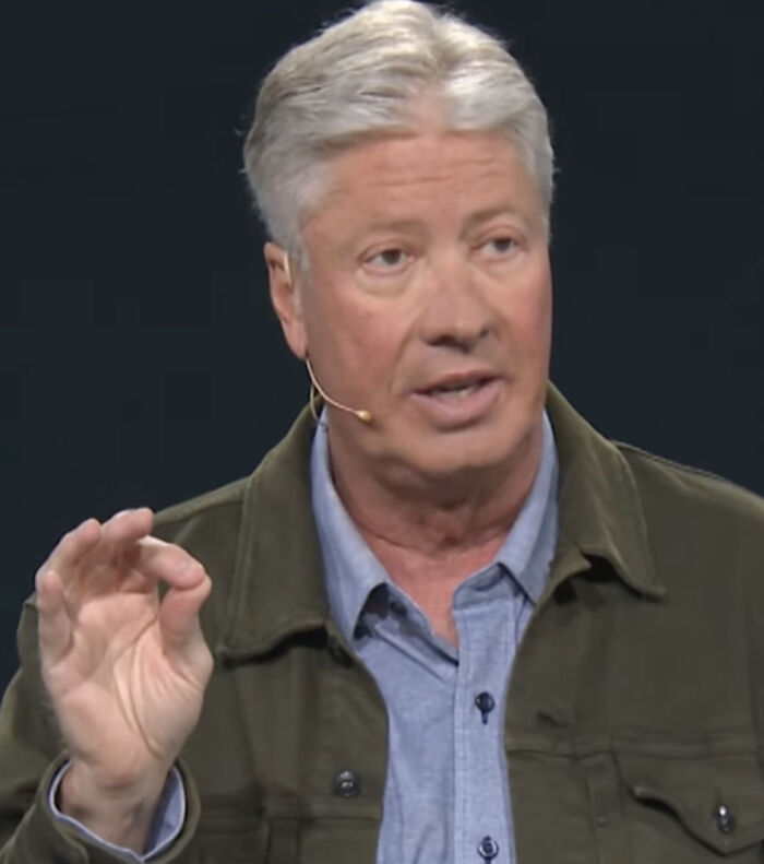 Texas megachurch pastor Robert Morris speaking during a sermon, wearing a green jacket and blue shirt.