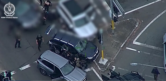 Police intercept a team of alleged assassins near vehicles at an urban intersection en route to daycare center.