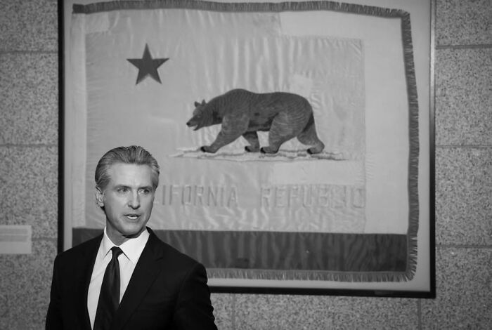 Gavin Newsom standing in front of California flag, symbolizing California politics and welcoming JD Vance.