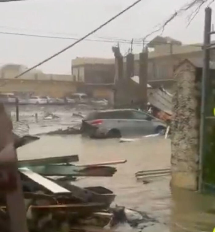 Flooded street with damaged cars and debris showcasing Hurricane Melissa devastation across Jamaica.