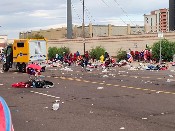 Trash and debris scattered on street after Trump rally mess with empty chairs and a parked emergency vehicle nearby