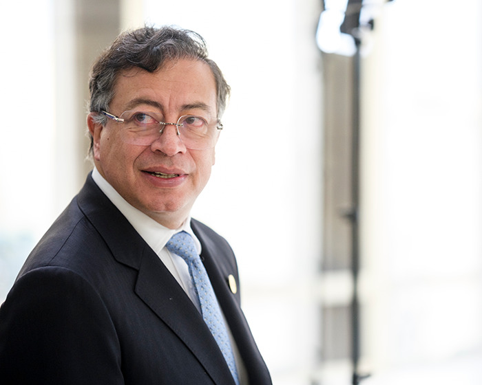 Colombia&rsquo;s president wearing glasses and suit, looking to the side in a bright indoor setting representing Venezuela analysis.