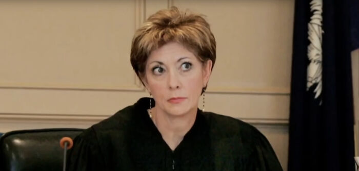 Judge in court wearing black robe with short hair, serious expression during a legal proceeding related to Trump case.
