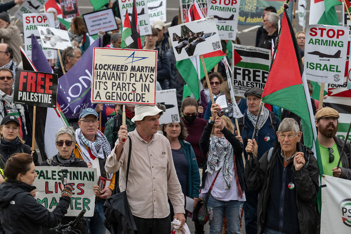 Protesters holding Palestinian flags and signs amid tensions over Hamas hostage release and Israel ceasefire doubts.