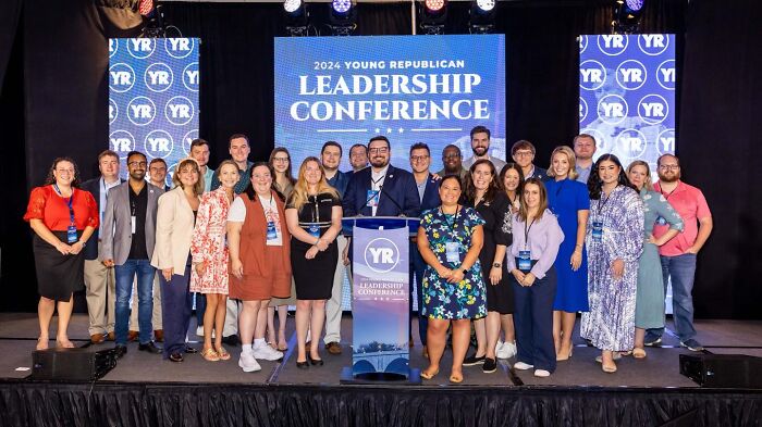 Group of young Republican leaders posing on stage at 2024 leadership conference amid racist remarks report controversy.