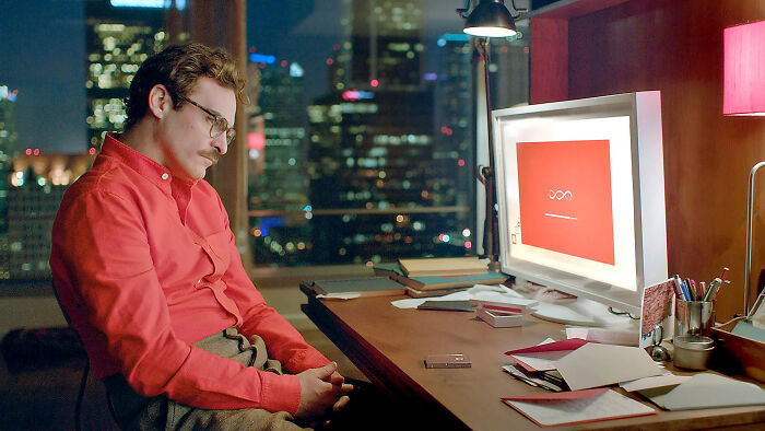 Man in a red shirt sitting at a desk with a computer, reflecting the internet&rsquo;s struggle to handle ChatGPT vibes.