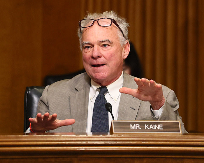 Senator speaking at a hearing, wearing glasses and a gray suit, warning about imminent war in Venezuela amid military buildup.