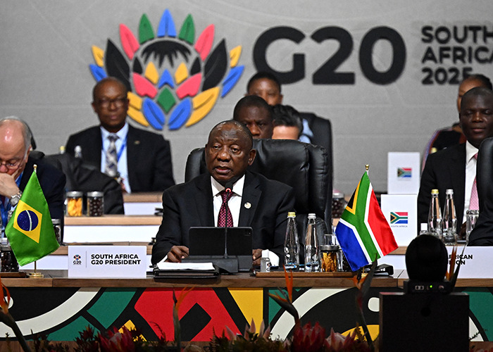 South Africa G20 President speaking at the summit, with flags and delegates discussing new energy and global cooperation.