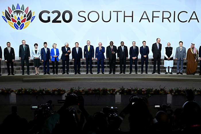 G20 leaders stand on stage at South Africa summit, highlighting new energy initiatives amid global power discussions.