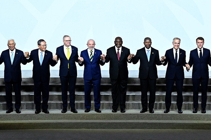 World leaders at G20 summit holding hands on stage, symbolizing unity and new energy collaboration efforts.