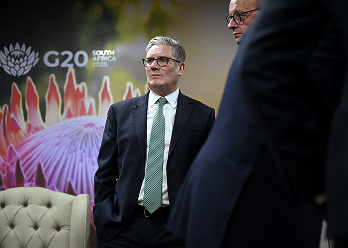 Man in suit and glasses at G20 summit, South Africa 2023, discussing energy policies as world leaders engage in talks.