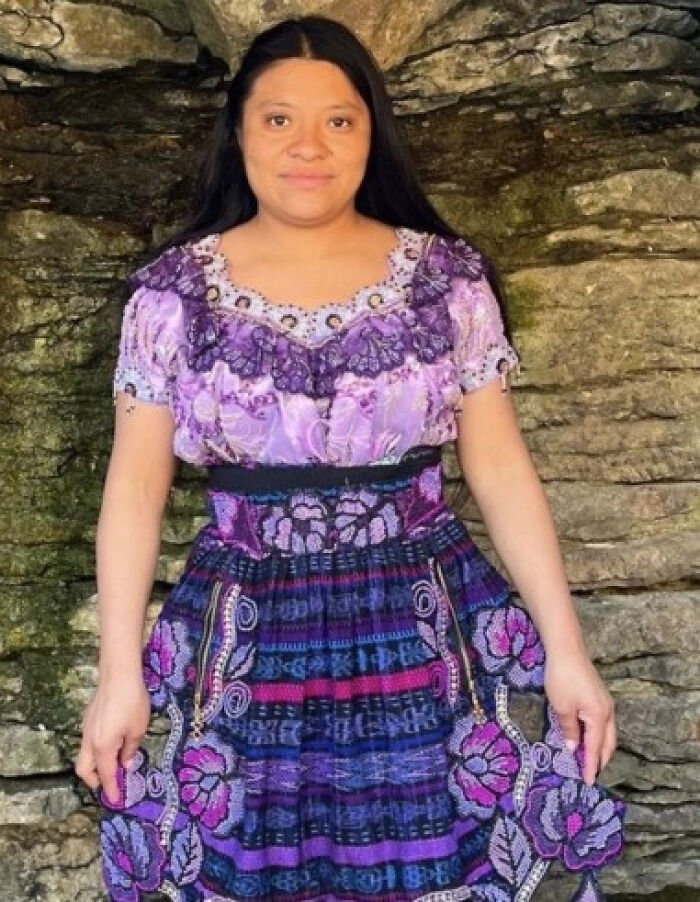 Woman in traditional purple dress standing against a stone wall related to Indiana man charged shooting house cleaner incident