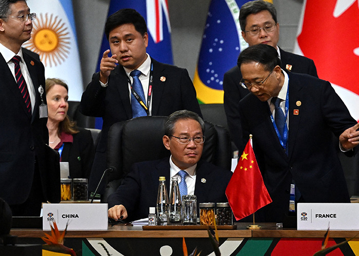 G20 leaders from China and France discussing new energy policies at an international summit with country flags visible.