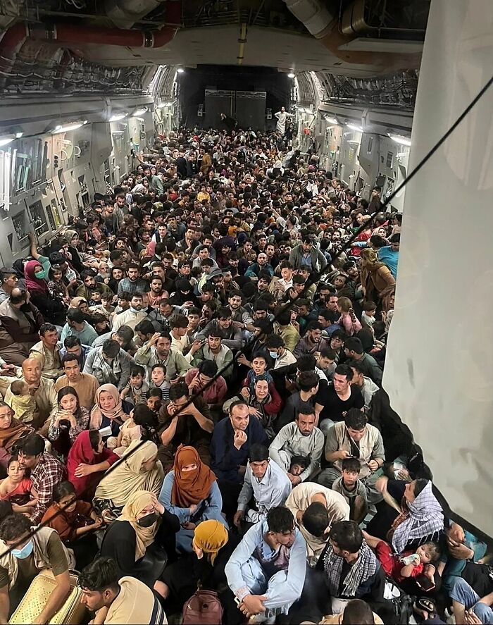 Large crowd of Afghan refugees inside a military aircraft during evacuation amid Afghan shooter exchange and Trump reporter insults.