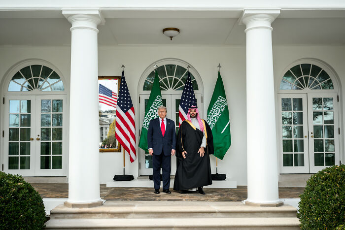 Donald Trump stands with Saudi prince under flags at White House, relating to Trump defending Saudi prince and Khashoggi controversy.