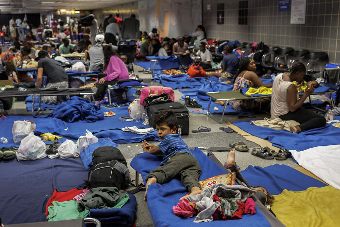 Migrants housed on cots inside airport terminal amid allegations of Biden administration forcing housing despite safety concerns.