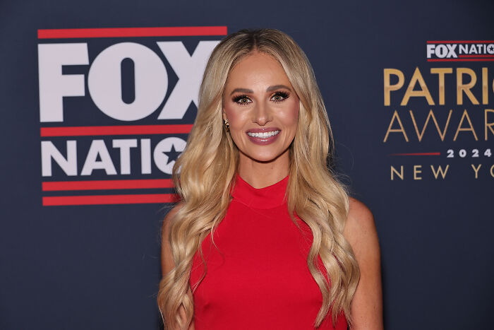 Tomi Lahren smiling in a red dress at a Fox Nation event, related to social media roasts and political discussions.