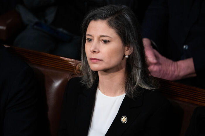 Woman in blazer seated indoors, appearing thoughtful during discussion on political violence and sedition concerns.