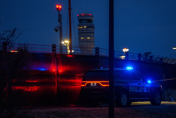 Police vehicle with flashing lights parked near a fence at night, related to parents jailed after 9-day-old baby incident.