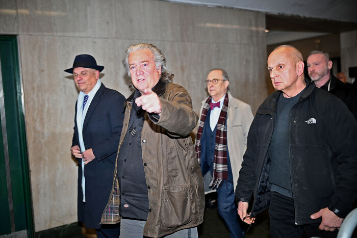 Steve Bannon walking with a group, pointing forward amid controversy over Republicans facing jail if they lose midterms