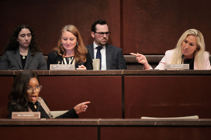 Jasmine Crockett speaking passionately while Marjorie Taylor Greene listens during a congressional hearing session.