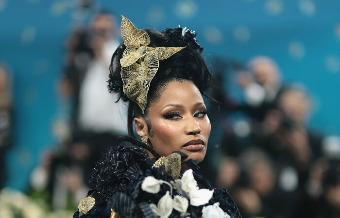 Nicki Minaj in an elaborate black outfit and gold headpiece amid photographers, sparking backlash over Trump administration ties