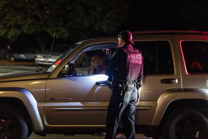 Police officer speaking to driver during a nighttime traffic stop illustrating traffic enforcement enforcement in America.
