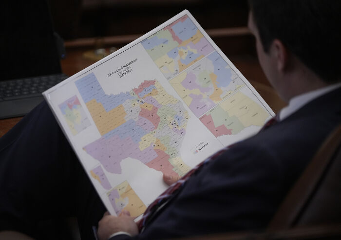 Person reviewing a color-coded Texas congressional district map related to federal court ruling on racial gerrymandering.