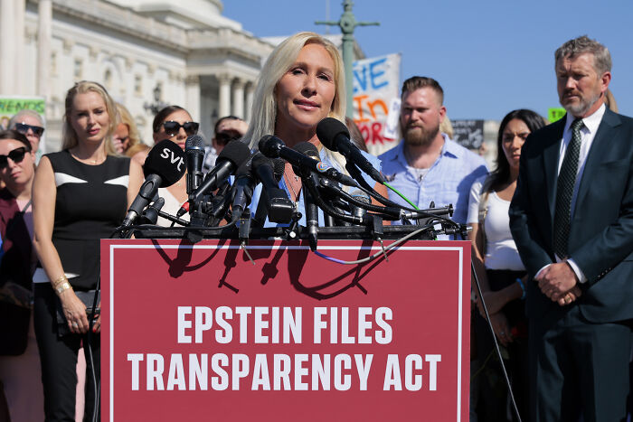 Marjorie Taylor Greene speaking at a press event about Epstein Files Transparency Act with supporters behind her.