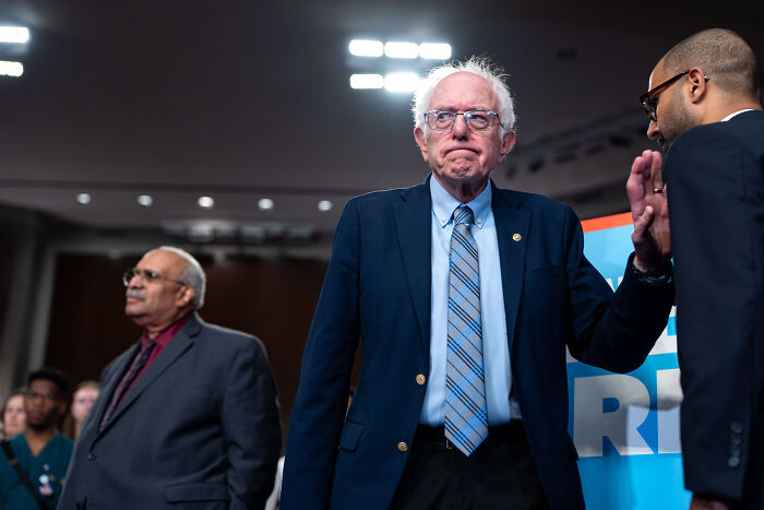 Older man in a blue suit and striped tie at a public event, symbolizing democratic socialism in NYC politics.
