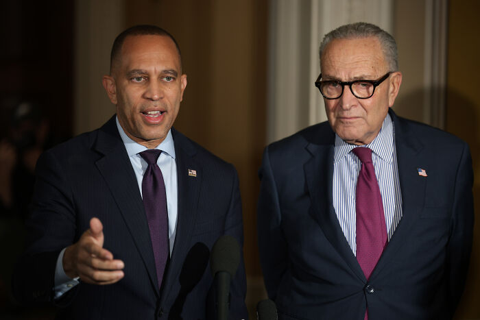 Two men in suits at a podium speaking during a political event, related to White House trolling Dems.