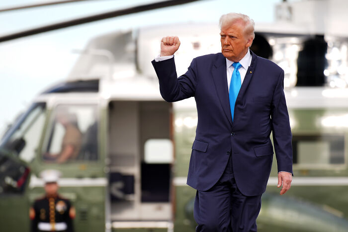 Former President Trump raising fist near helicopter, amid Swifties outrage over music use and lyric changes by Team Trump.