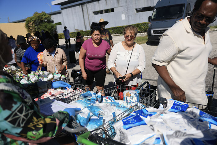 People gathering food items at a SNAP benefits distribution event amid controversy over ignoring court orders.