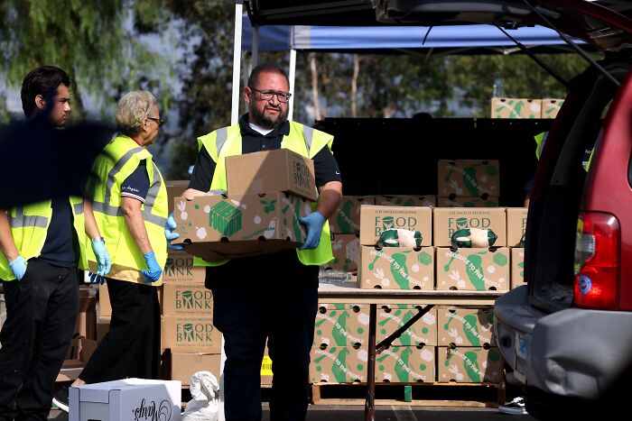 Volunteers wearing safety vests unload food bank boxes for SNAP recipients ahead of Thanksgiving holiday assistance.