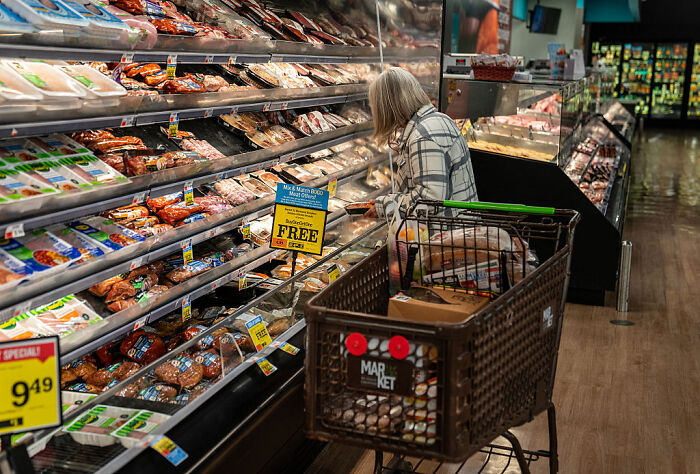 Older woman shopping with a cart in grocery store aisle, reflecting changes in Trump&rsquo;s approval on key MAGA political issues.