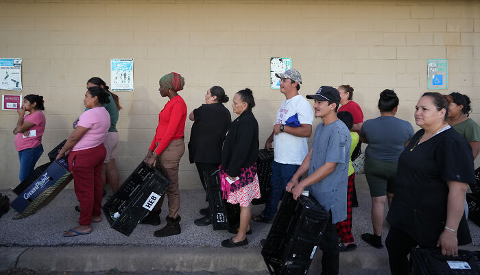 People waiting in line carrying black crates to receive SNAP benefits ahead of Thanksgiving holiday assistance.
