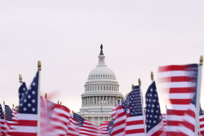 U.S. Capitol building with multiple American flags in foreground symbolizing the battle for House seats ahead of midterms.