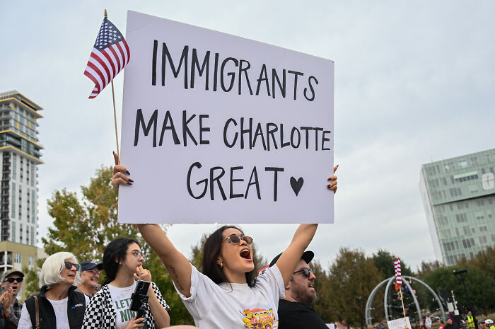 Protesters in Charlotte holding signs supporting immigrants during a rally against ICE raids and immigration policies.