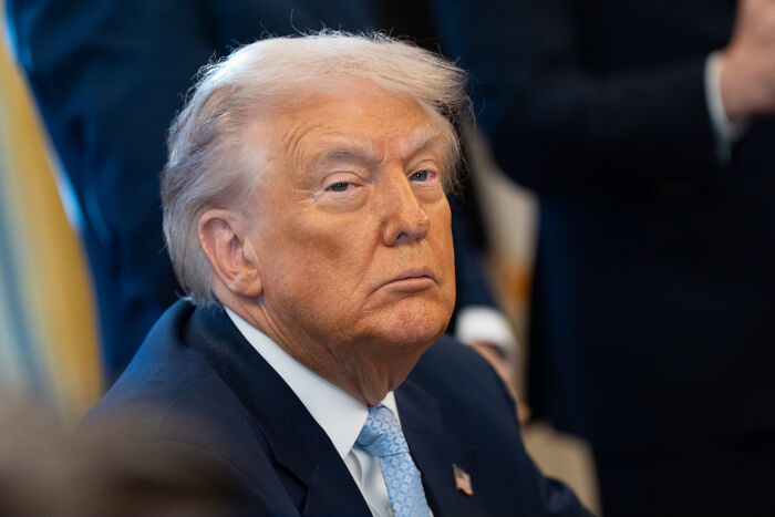 Donald Trump in a suit and blue tie, looking serious during a formal event discussing dementia concerns from family claims.