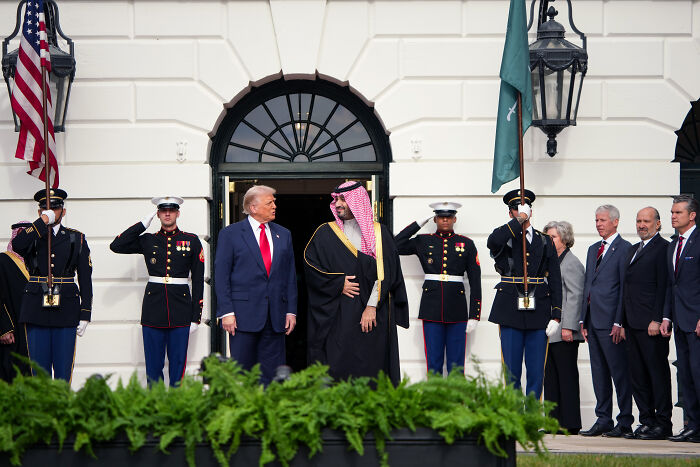 Donald Trump and Saudi Crown Prince standing outside White House with military honor guards during official event.