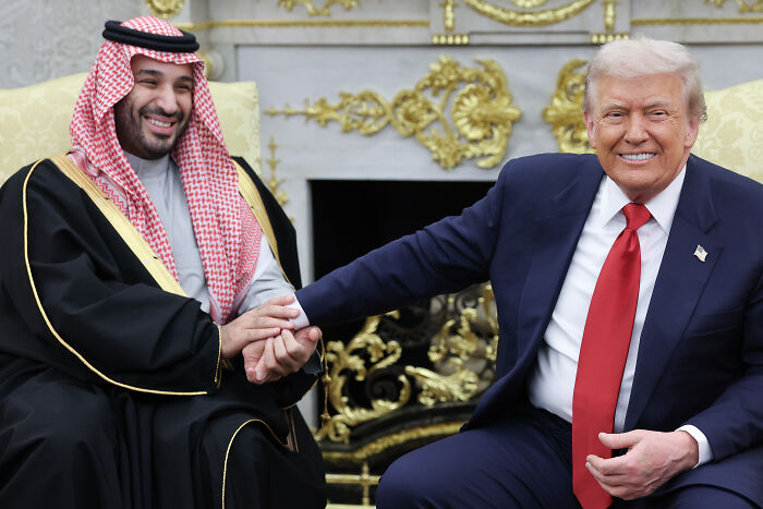 Donald Trump shaking hands with Saudi prince in formal setting amid Khashoggi controversy and defense statements.
