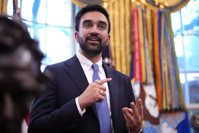 Zohran Mamdani speaking inside the White House, wearing a suit and tie, sharing insights on a unique experience.