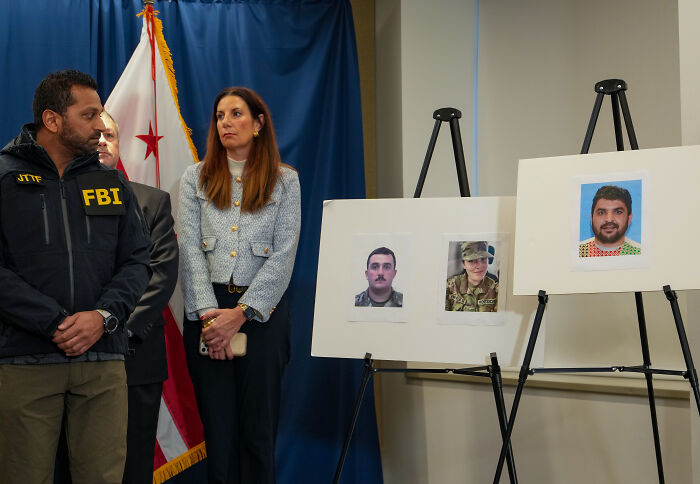 FBI agent and officials stand beside photos of Afghan shooter during press briefing on recent exchange and investigation.